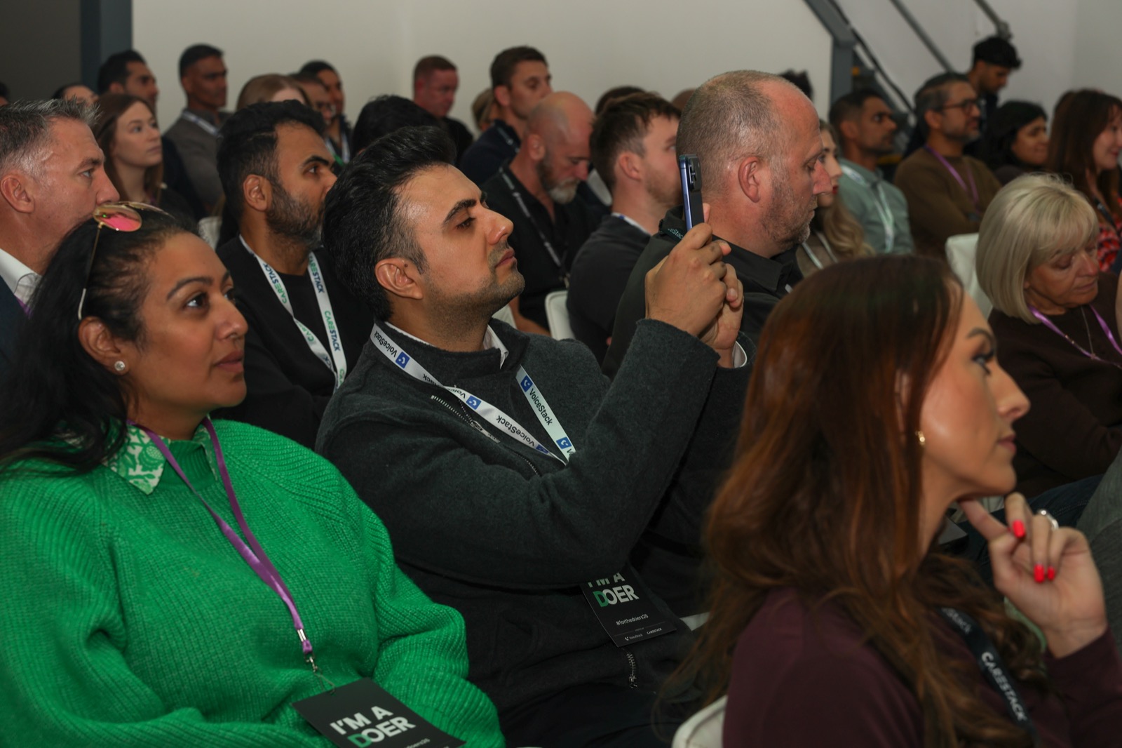 Delegates watching a presentation at For the Doers 2026, with one attendee taking a photograph.